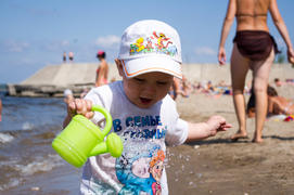 Ребёнок играет с лейкой на пляже
