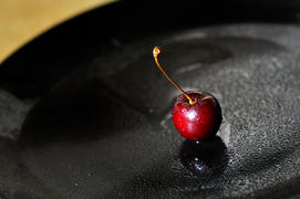 Ягода черешни на чёрном блюде