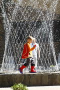 Ребенок в костюме мушкетера играет у фонтана 