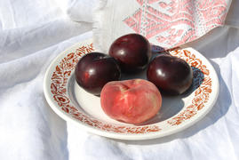 Один персик и три сливы лежат на тарелке