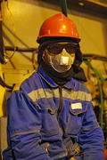 The worker in overalls and a respirator. Protective attire of technical workers