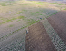 Вид сверху на трактор, который пашет поле. 