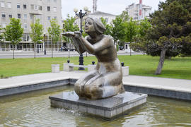 Статуя коленопреклоненной женщины в фонтане. Вода, стекающая с руки статуи.