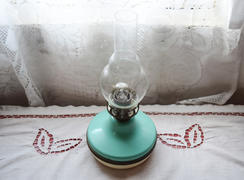 Керосиновая лампа на столе возле окна.