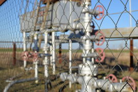 Grid the chain-link near an oil well. Shutoff valves and service equipment