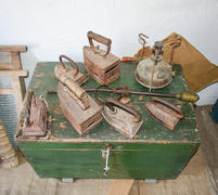 Старинные утюги на деревянном сундуке 
