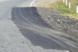 Repair of an asphalt road surfacing. A patch on the asphalt