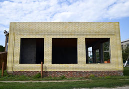 House under construction from yellow bricks. The walls of an unfinished house.
