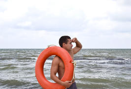 Человек на пляже с спасательным кругом  