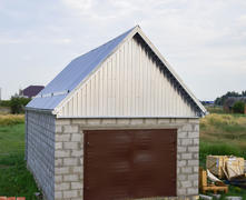 Small garage with a roof of corrugated sheet metal. Garage with steel gates.