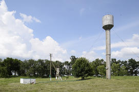 Серебряный водонапорная башня среди зеленой травы и деревьев. 2