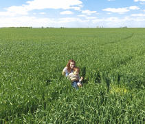 Молодая девушка с ребенком сидит в траве на поле.