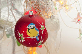 Red christmas toy with bullfinches in the form of a ball hanging on a branch