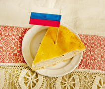 one piece of Russian pie with fish lying on a plate with a patriotic flag