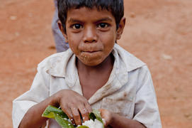 Indian village boy eats rice arms