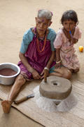 Grandmother and granddaughter make flour using a hand mill