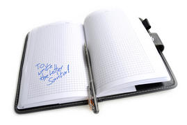 Записная книга с ручкой, на белом фоне.