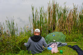 Рыбак с удочкой на берегу горного озера