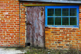  Старые неокрашенные, разрушенные и обветшалые двери в кирпичном сарае