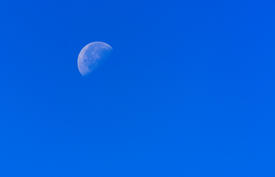Луна в небе в солнечный день в ярком синем небе