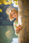 Smiling blonde girl in park with leaves in hands