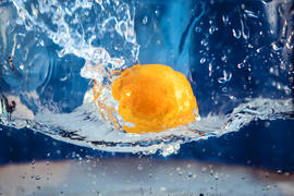 Желтый апельсин падает в воду