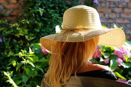 Девушка в шляпе, сидит в саду