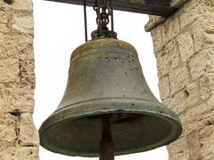 The ancient bell hangs on an ancient wall and never calls