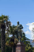 The monument to Lenin is among palm trees and against the bright blue sky