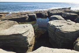 Rocks and sea meet in the bright sunlight in autumn
