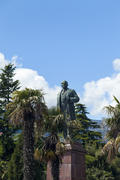The monument to Lenin is among palm trees and against the bright blue sky