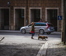 Женщина выгуливает длинношёрстную таксу на улице Стокгольма