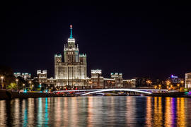 Вид на фасад одной из сталинских высоток Москвы через реку вечером, Россия