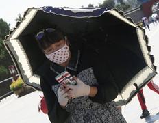 Пекин. Женщина с зонтом и в повязке.