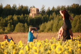 Молодой человек фотографирует пару в поле подсолнечника