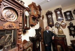 Коллекционер в окружении старинных механических часов 