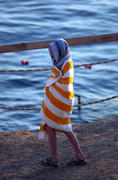 Ребенок на пляже завернулся в полотенце и гуляет