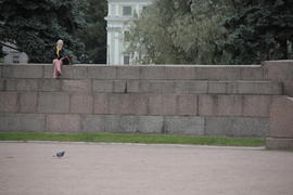 Девушка сидит на высокой каменной стене 
