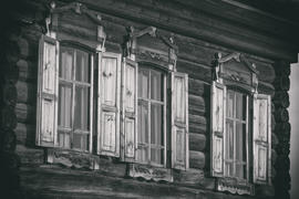 Три окна бревенчатого дома с резными наличниками и ставнями